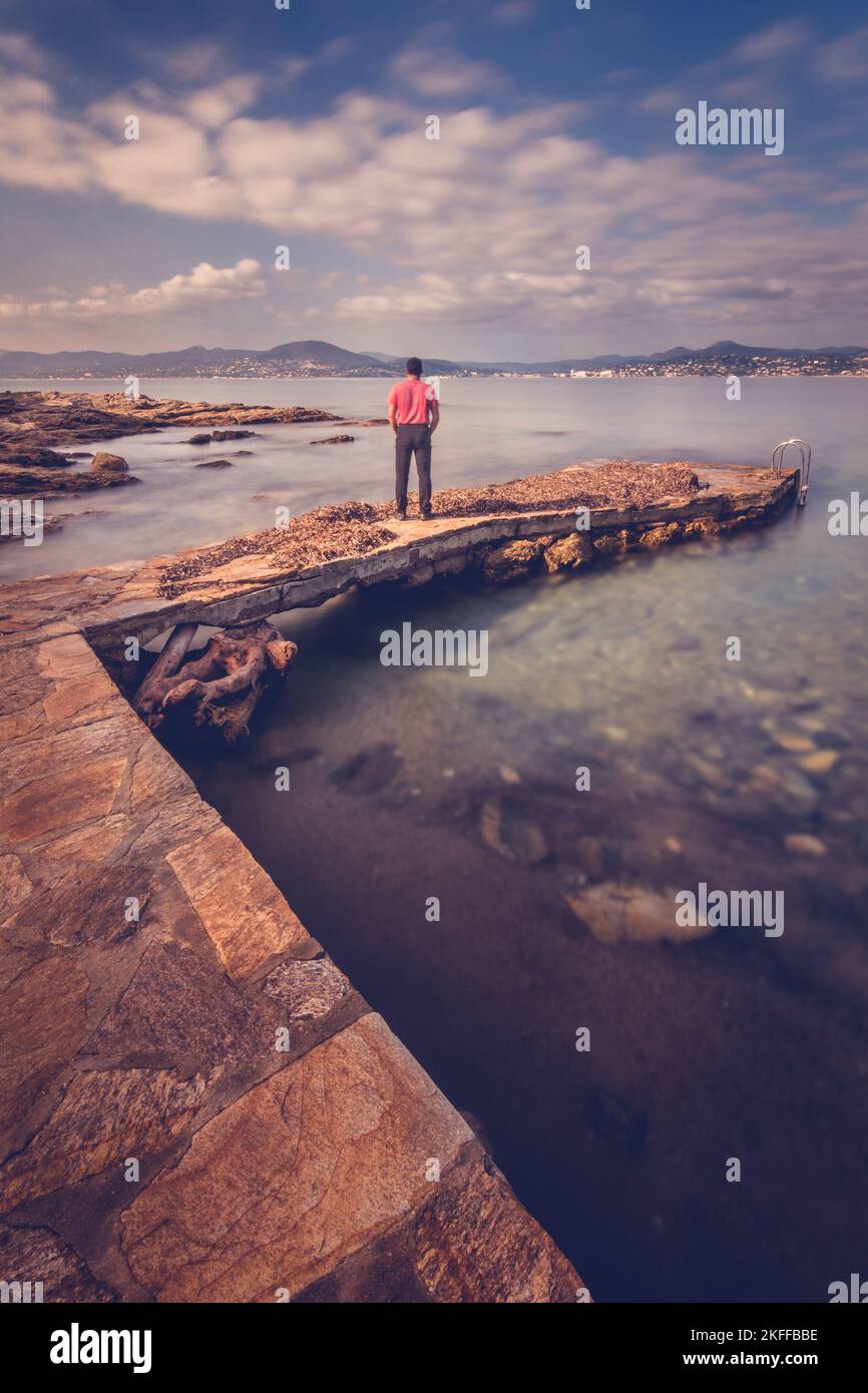 Vista panoramica del giovane in piedi sul molo che guarda direttamente al paesaggio del mare Mediterraneo nella baia di Saint Tropez Foto Stock