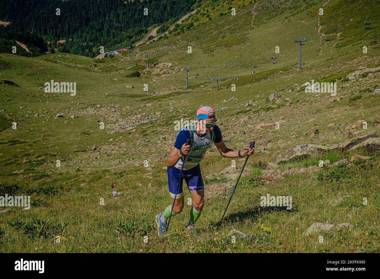 Rosa Khutor, Russia - 10 settembre 2022: Atleta maschile con bastoni da trekking in salita nel Sentiero Rosa Wild Foto Stock