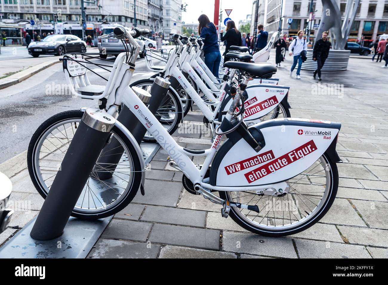 Vienna, Austria - 14 ottobre 2022: Una fila di biciclette elettriche a noleggio con pubblicità da Wien Mobil carica le batterie nei loro supporti docking con pe Foto Stock