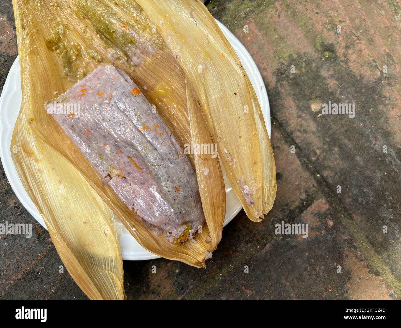 Tamale prodotto da mais blu con fiori di zucca avvolti in una buccia di mais a Oaxaca, Messico. Cibo Oaxacan fatto in casa. Foto Stock