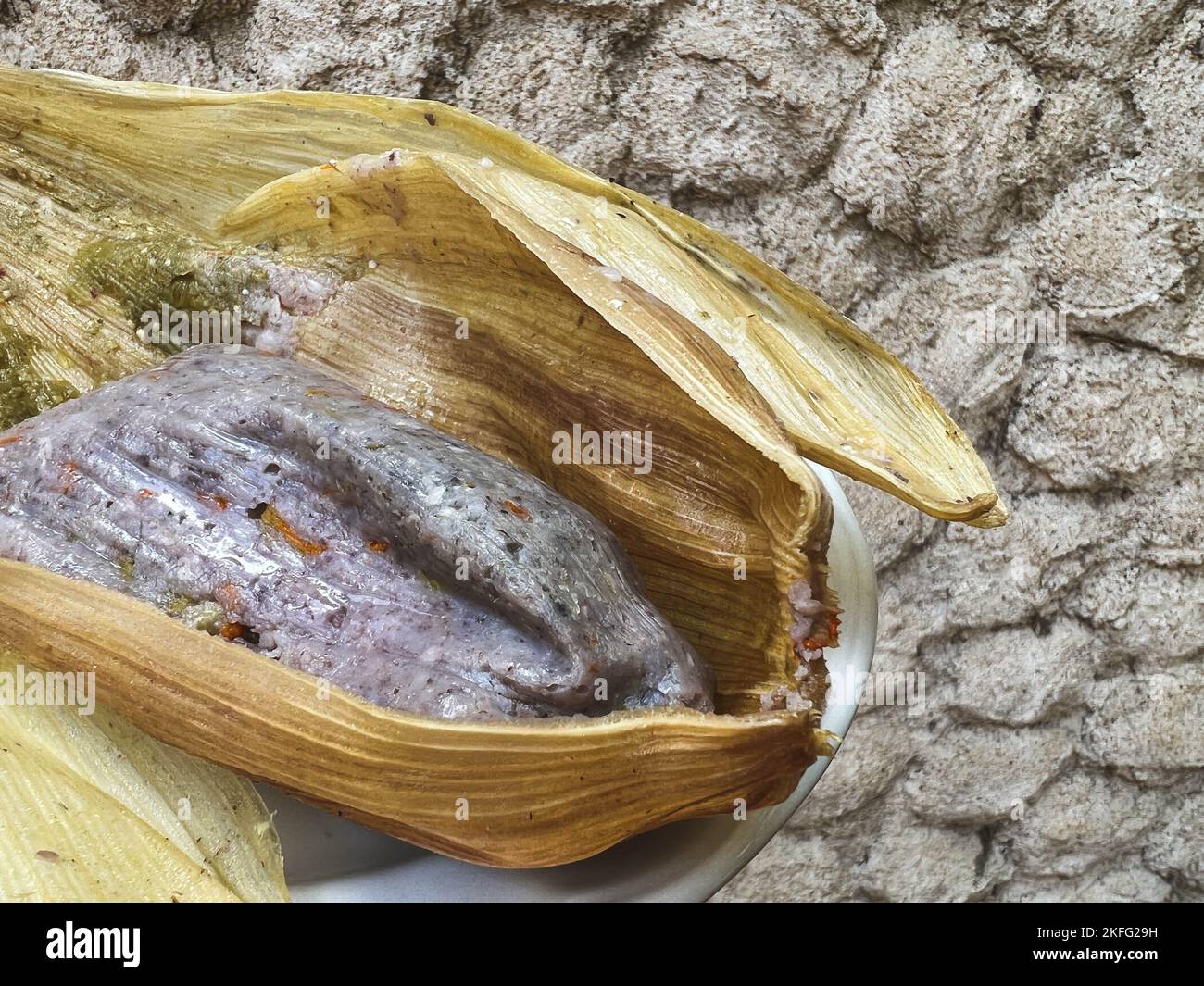Tamale prodotto da mais blu con fiori di zucca avvolti in una buccia di mais a Oaxaca, Messico. Cibo Oaxacan fatto in casa. Foto Stock