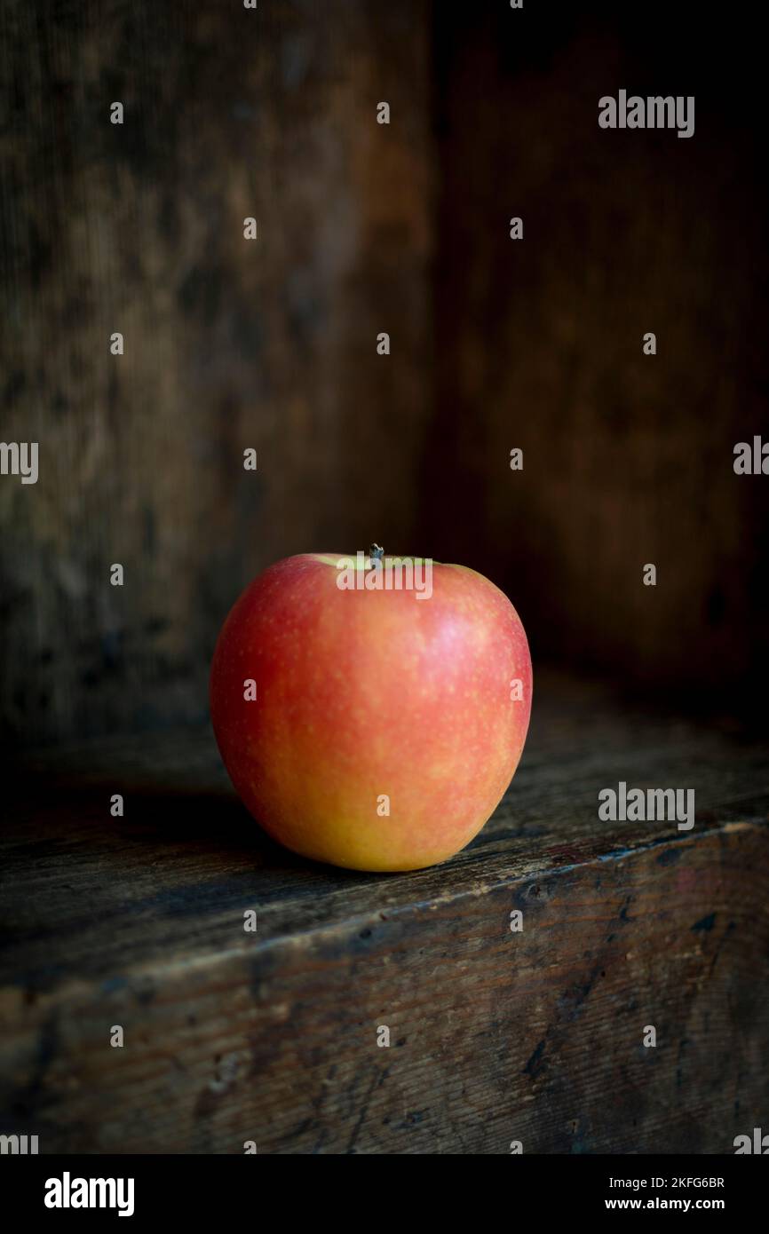 Foto verticale di una mela con un vecchio sfondo di legno Foto Stock