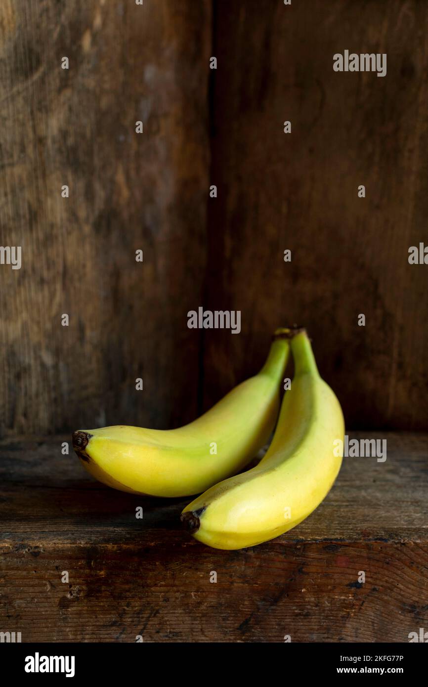 Colpo verticale di due banane con un vecchio sfondo di legno Foto Stock