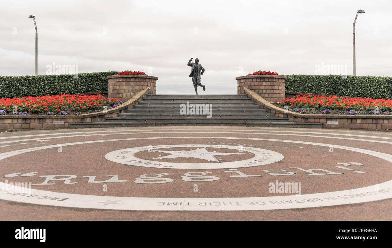 Statua di Eric Morecambe sul fronte di Morcambe se, regno unito. Famosa scultura d'arte con fiori simmetrici, pietre di pavimentazione laterali e circolari. Foto Stock