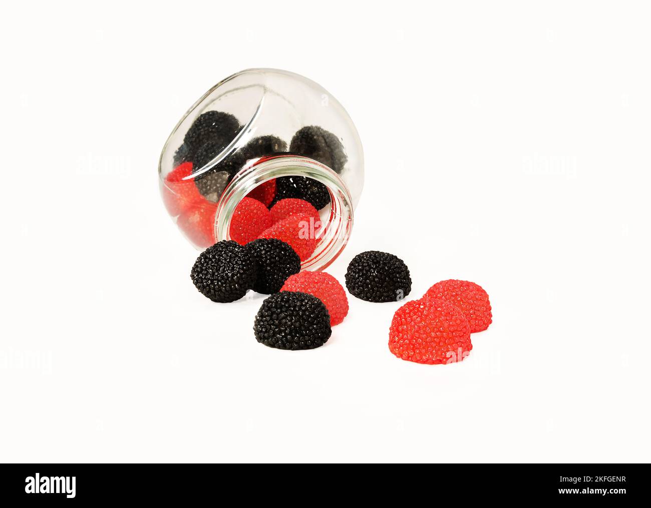 Gelatine dolci di succo di frutta nera e rossa a forma di more e lamponi che si riversano da un vasetto. Foto Stock