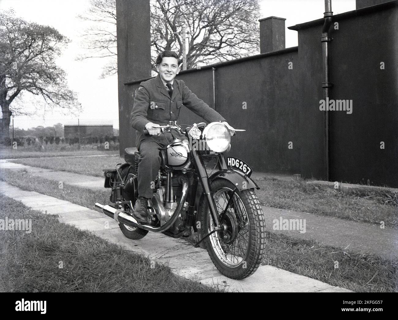 1948, storico, un giovane RAF NCO nella sua divisa seduta su una moto Norton fabbricata in Inghilterra, fuori a RAF Ternhill, Longford Camp, Market Drayton, Shropshire, Inghilterra, Regno Unito la base aerea fu aperta nel 1916 ma chiusa nel 1922, fu richiesta nuovamente nel 1935 quando il programma di espansione RAF si avviò con la guerra all'orizzonte. Foto Stock