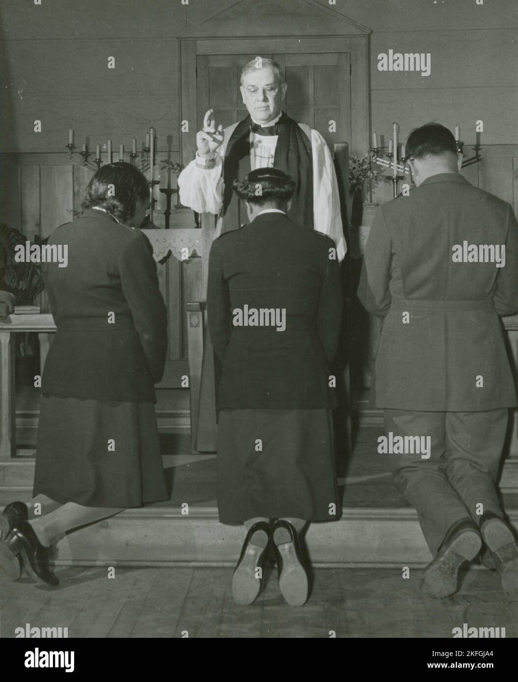 Vescovo episcopale che conferma i tenenti afroamericani Rosemary Vincent e Hallie M. Brown e un soldato non identificato, mentre si inginocchiano davanti a lui, 1939 - 1945. Foto Stock