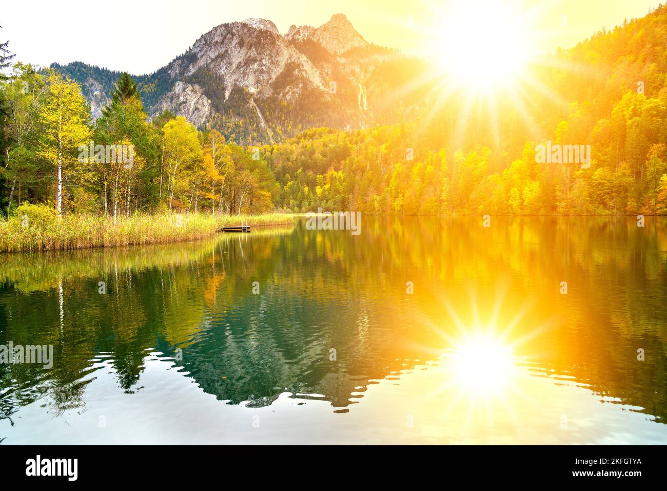 paesaggio panoramico con lago, catena montuosa e sole sul cielo Foto Stock