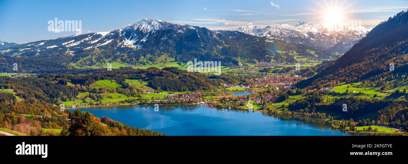 paesaggio panoramico con lago, catena montuosa e sole sul cielo Foto Stock