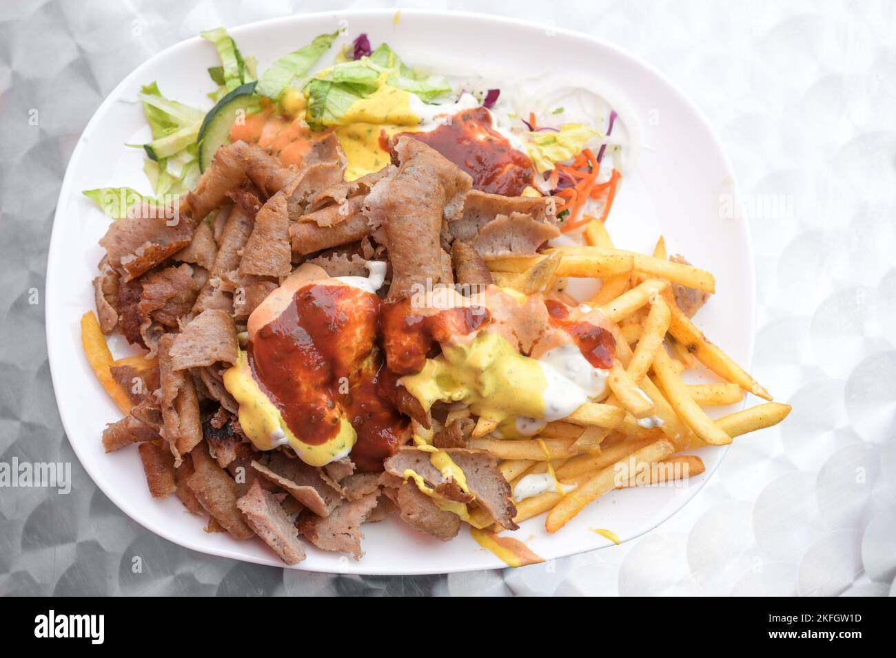 Doner kebab su un piatto con patatine fritte, insalata e salse varie, popolare fast food dalla cucina turca, spazio copia, vista ad angolo alto dall'alto, se Foto Stock
