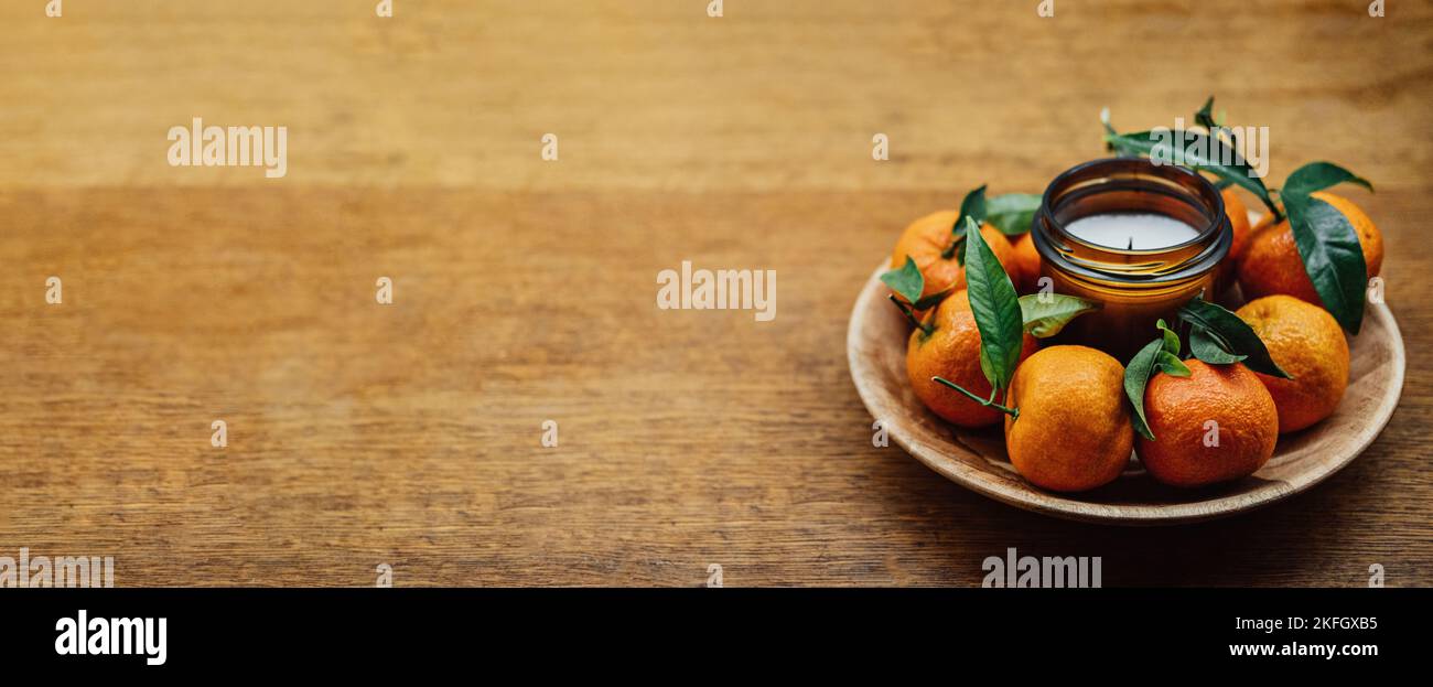 Candele di Natale per le feste. Candela di agrumi e arance succose sul tavolo in legno della cucina. Nuova Home candela di Natale Giara di candela personalizzata. Foto Stock