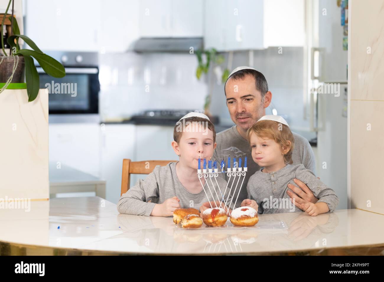 Padre e figli con la menorah celebrano hanukkah - festa religiosa ebraica Foto Stock
