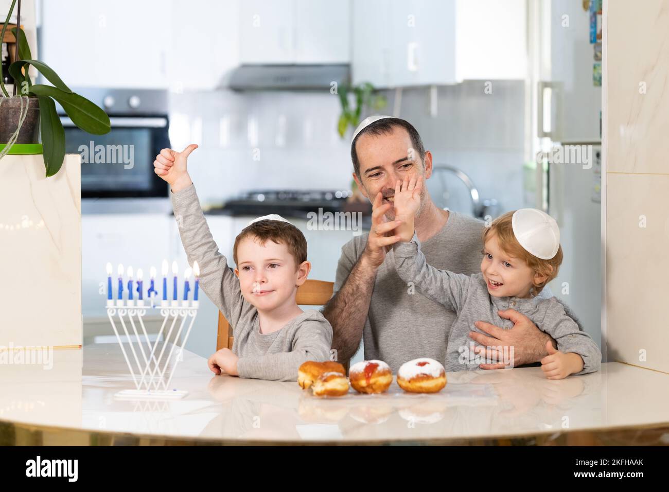 Padre e figli con la menorah celebrano hanukkah - festa religiosa ebraica Foto Stock
