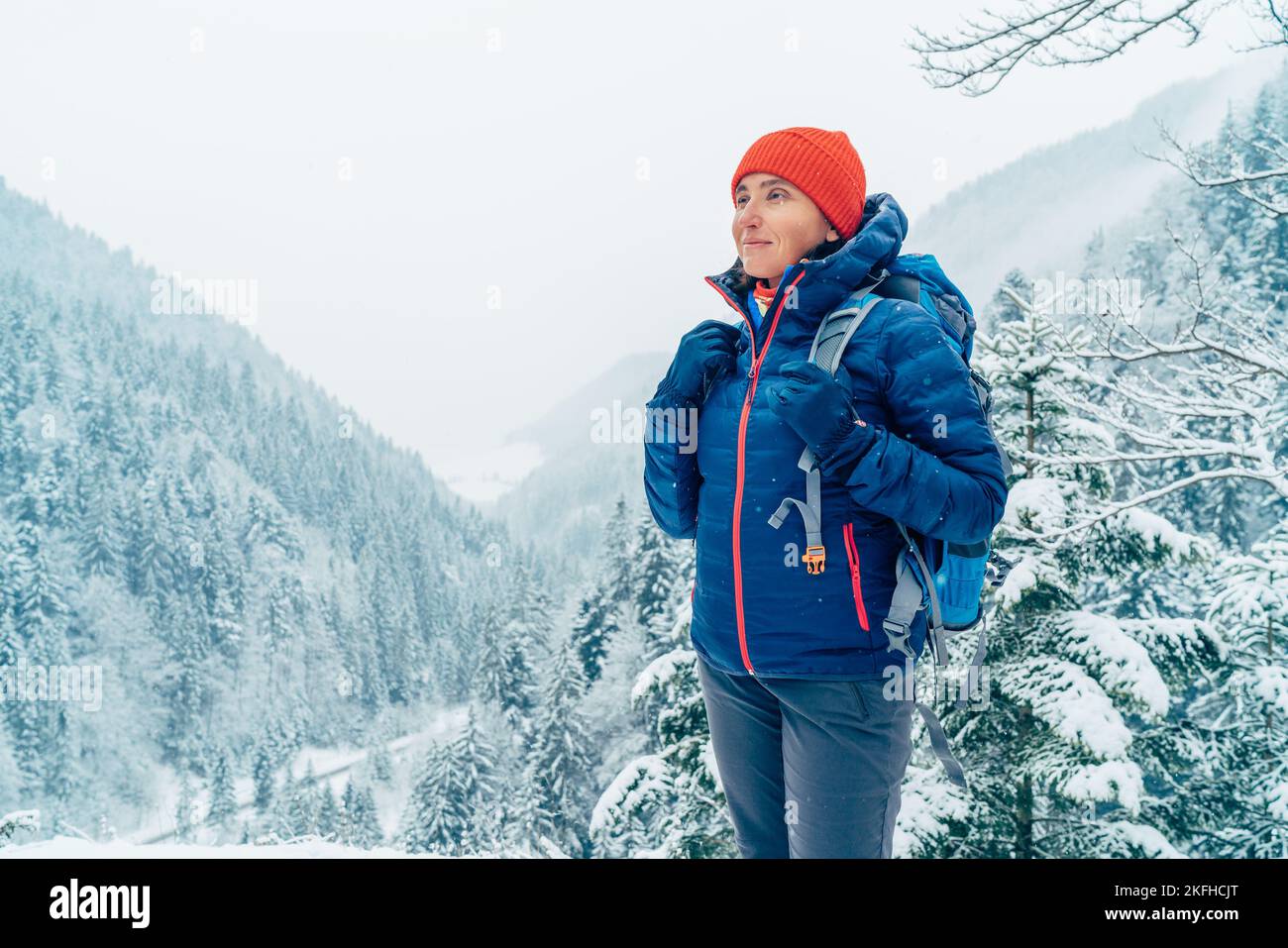 Donna zaino con zaino vestito caldo giubbotto godendo neve montagna  paesaggio, mentre lei trekking inverno montagna percorso forestale. pe  attivo Foto stock - Alamy