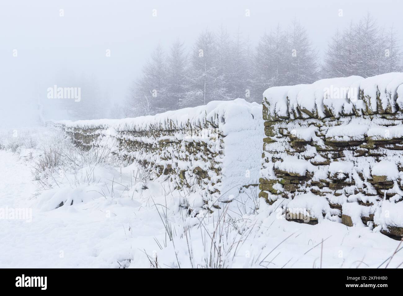 Muro di pietra a secco nella campagna britannica in inverno, coperto di neve. Blizzard neve e paesaggio invernale con pareti rustiche in pietra. Foto Stock