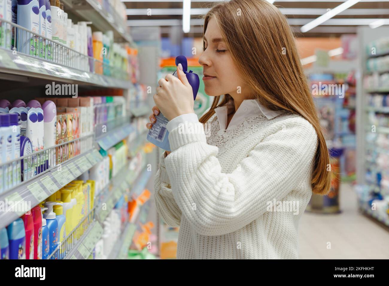 La giovane madre caucasica sceglie lo shampoo per bambini e il gel doccia nel supermercato Foto Stock