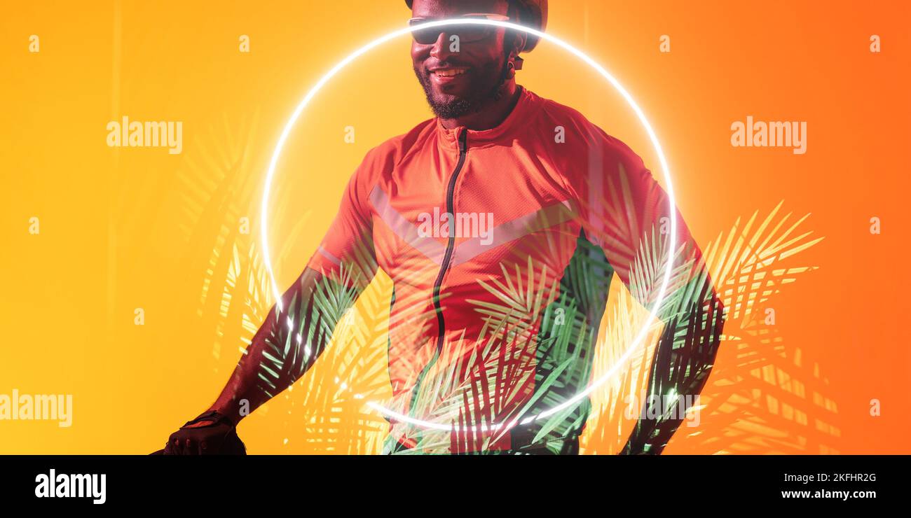 Ciclista afro-americana sorridente con occhialini illuminati a cerchio e piante Foto Stock