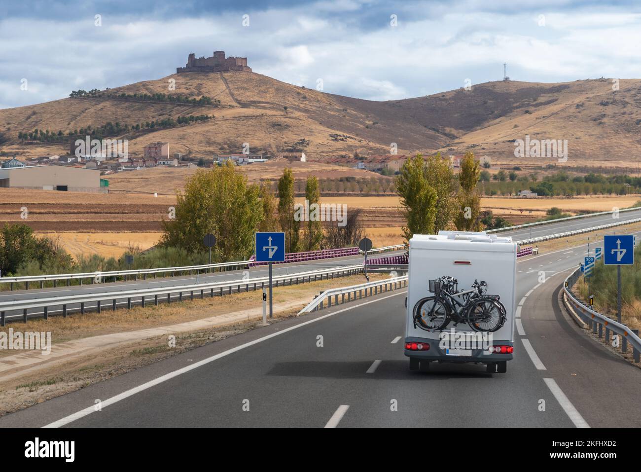 Camper guidando lungo un'autostrada con il castello di Almonacid de Toledo sullo sfondo. Foto Stock