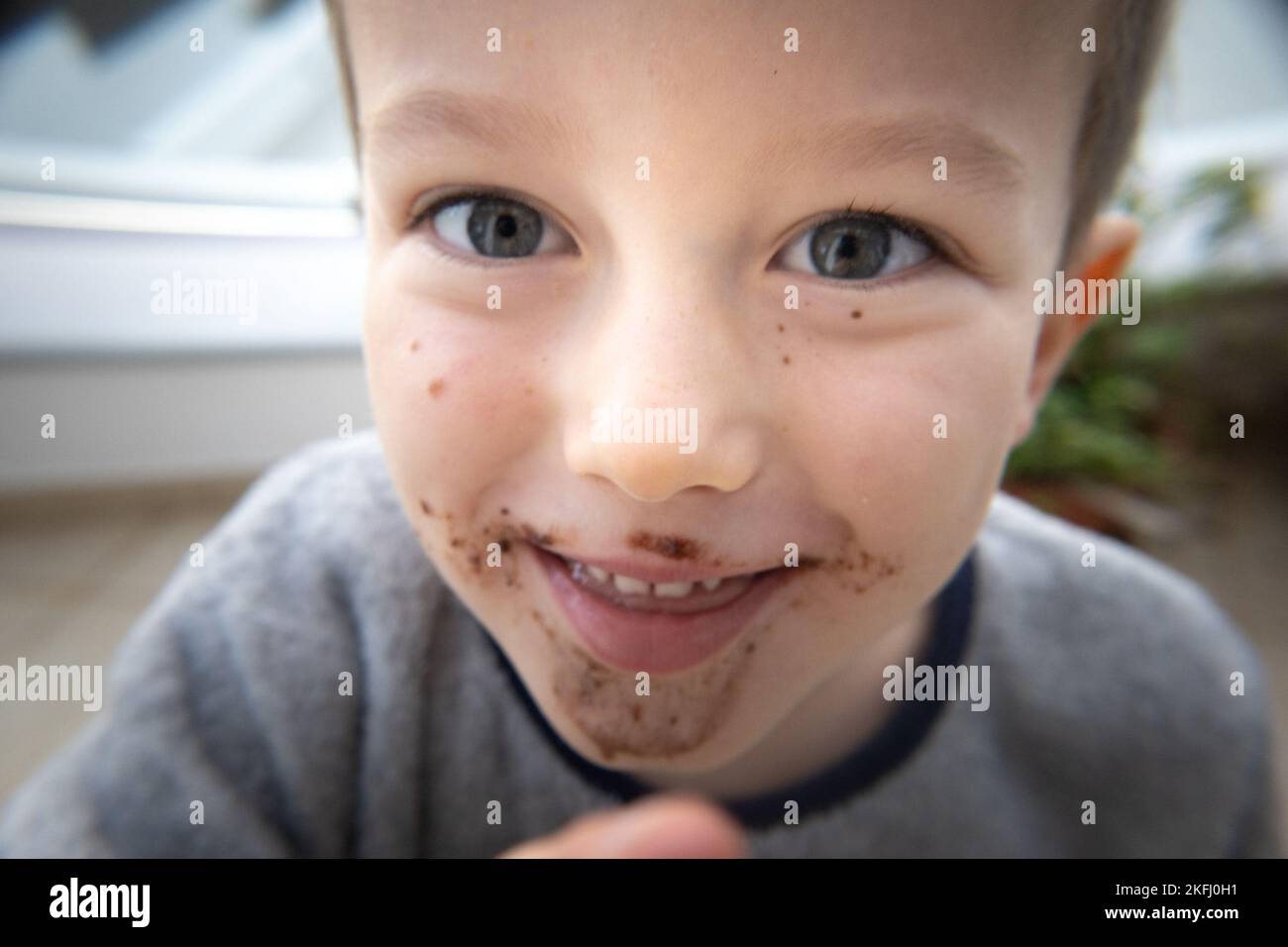Primo piano ritratto di carino ragazzo elementare spensierato con bocca sudicia sorridente all'aperto Foto Stock