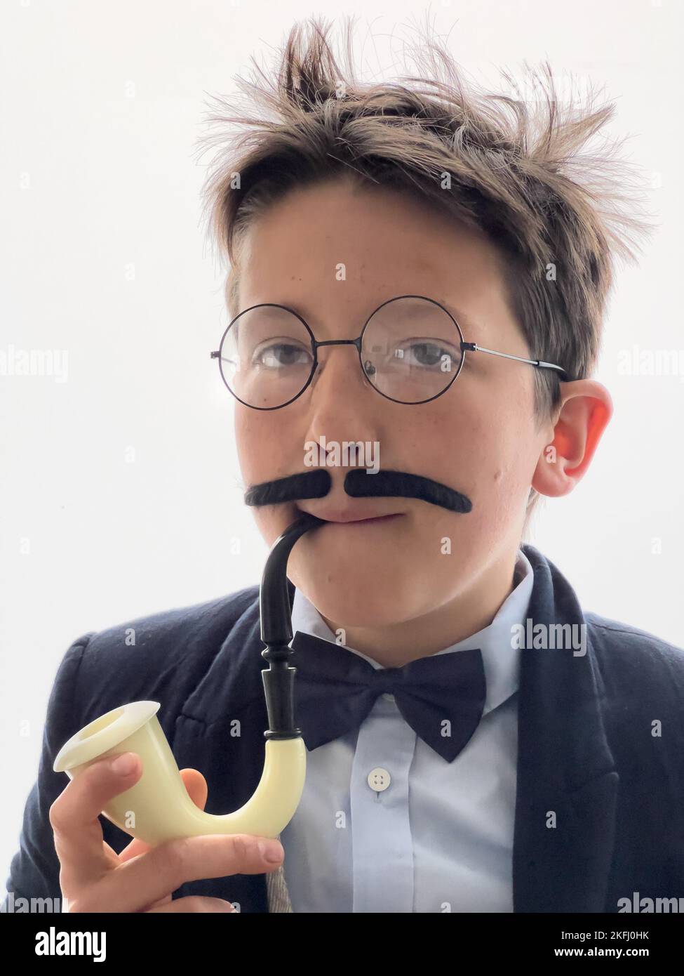 Primo piano ritratto di ragazzo con i capelli tousled indossare costume detective e fumo con tubo su sfondo bianco Foto Stock