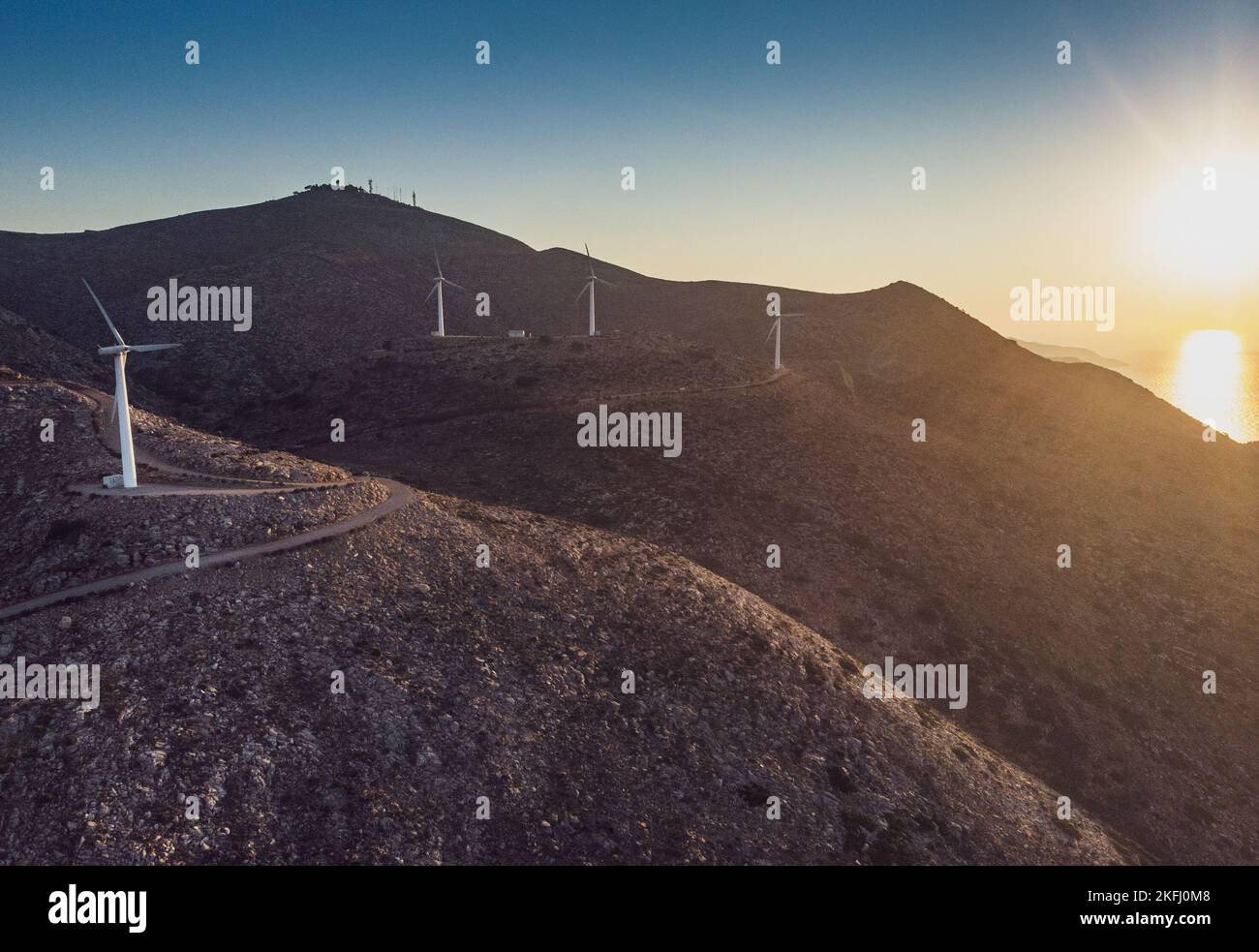 Turbine eoliche sulla catena montuosa e vista panoramica del paesaggio contro il cielo durante il tramonto Foto Stock