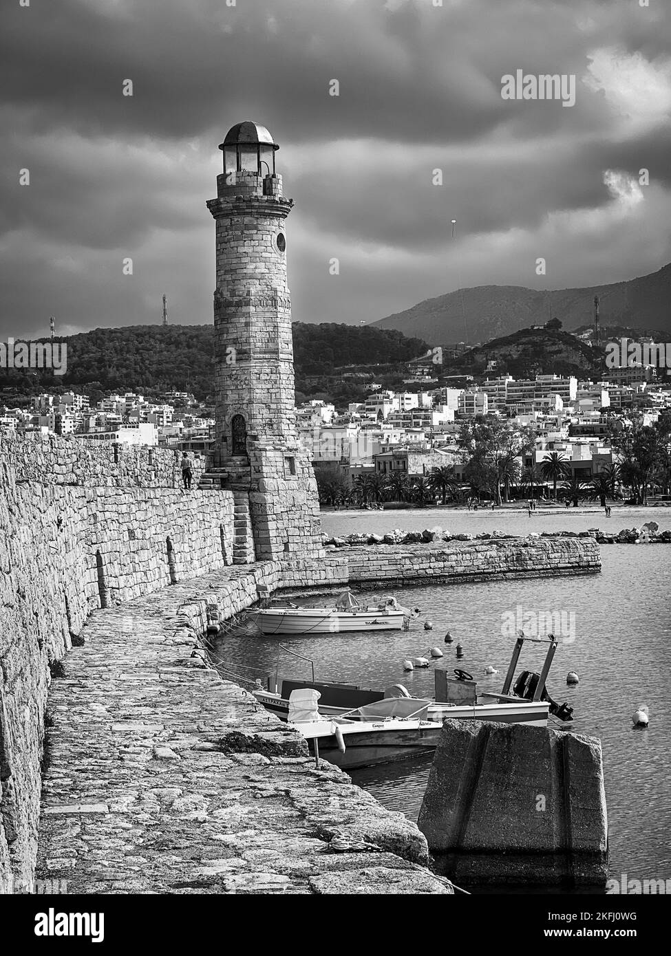 Vista dello storico faro di la Canea al porto sull'isola di Creta contro la città e il cielo nuvoloso durante la tempesta Foto Stock