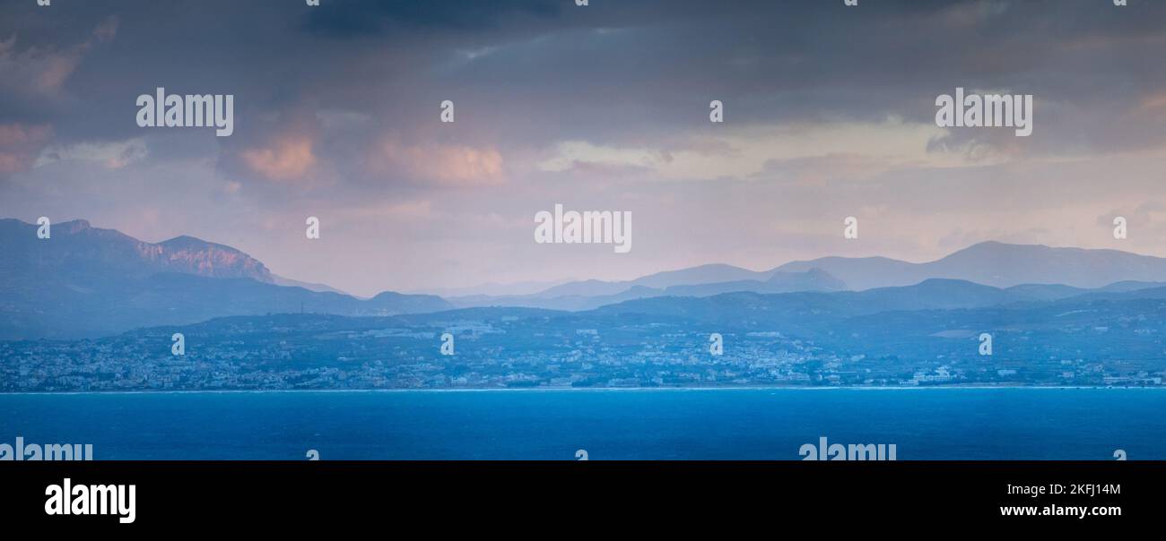 Vista panoramica e tranquilla del mare e delle silhouette delle montagne contro il paesaggio nuvoloso durante il tramonto Foto Stock