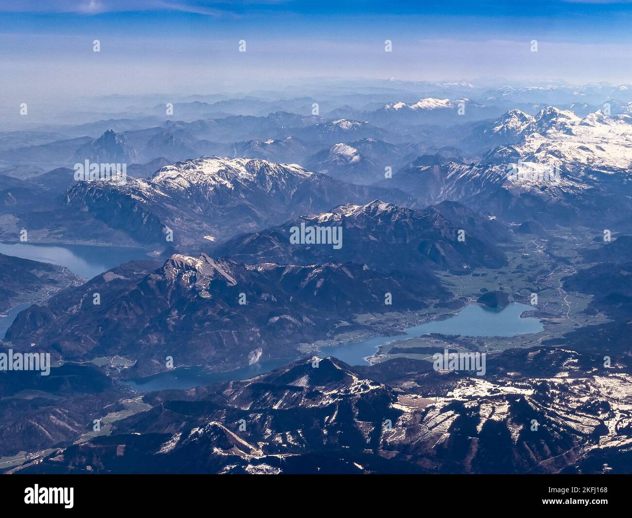 Vista panoramica della splendida catena montuosa delle Alpi europee innevate e del lago con cielo blu sullo sfondo Foto Stock