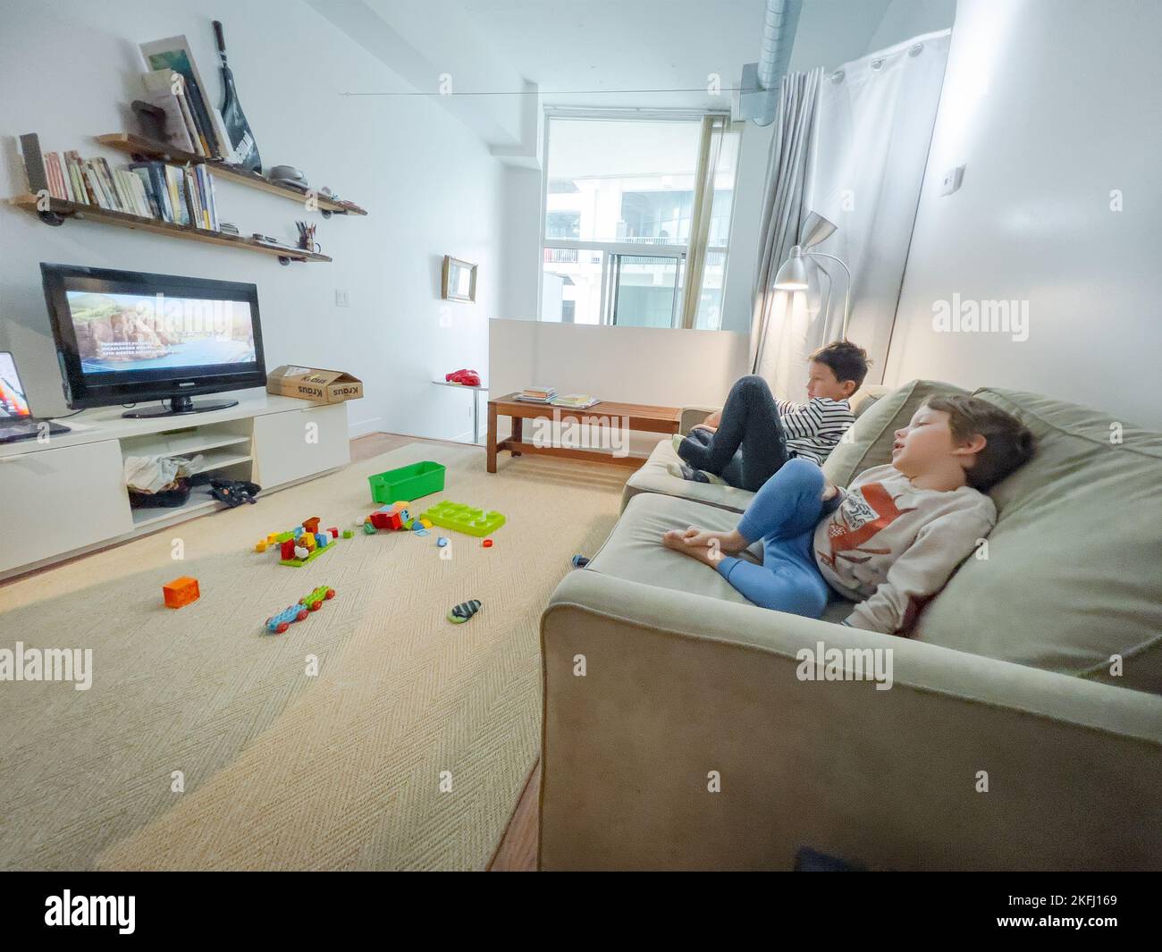 I fratelli caucasici guardano la TV mentre si rilassano insieme sul divano nel soggiorno di casa durante il fine settimana Foto Stock