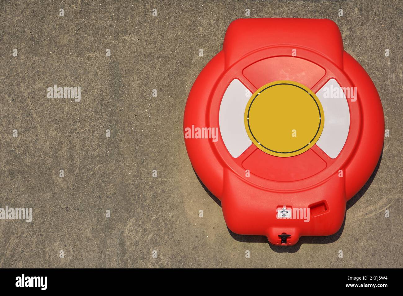 Vita Buoy attaccato a muro di cemento in pietra. Casella rossa con cerchio interno giallo Foto Stock