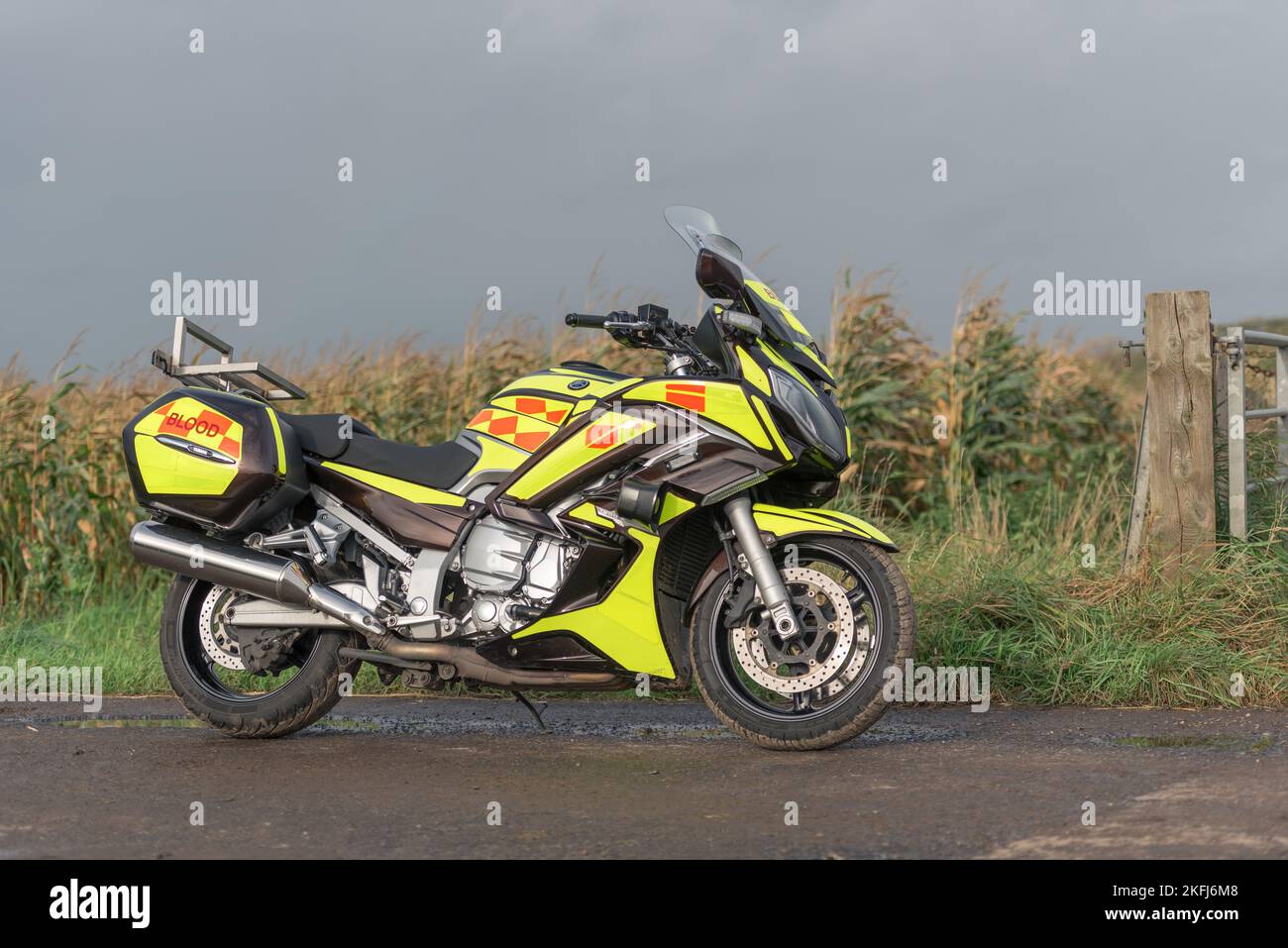 Blood Bike liveried. North West Blood Bikes a lato della strada, chevron gialli e arancioni Foto Stock