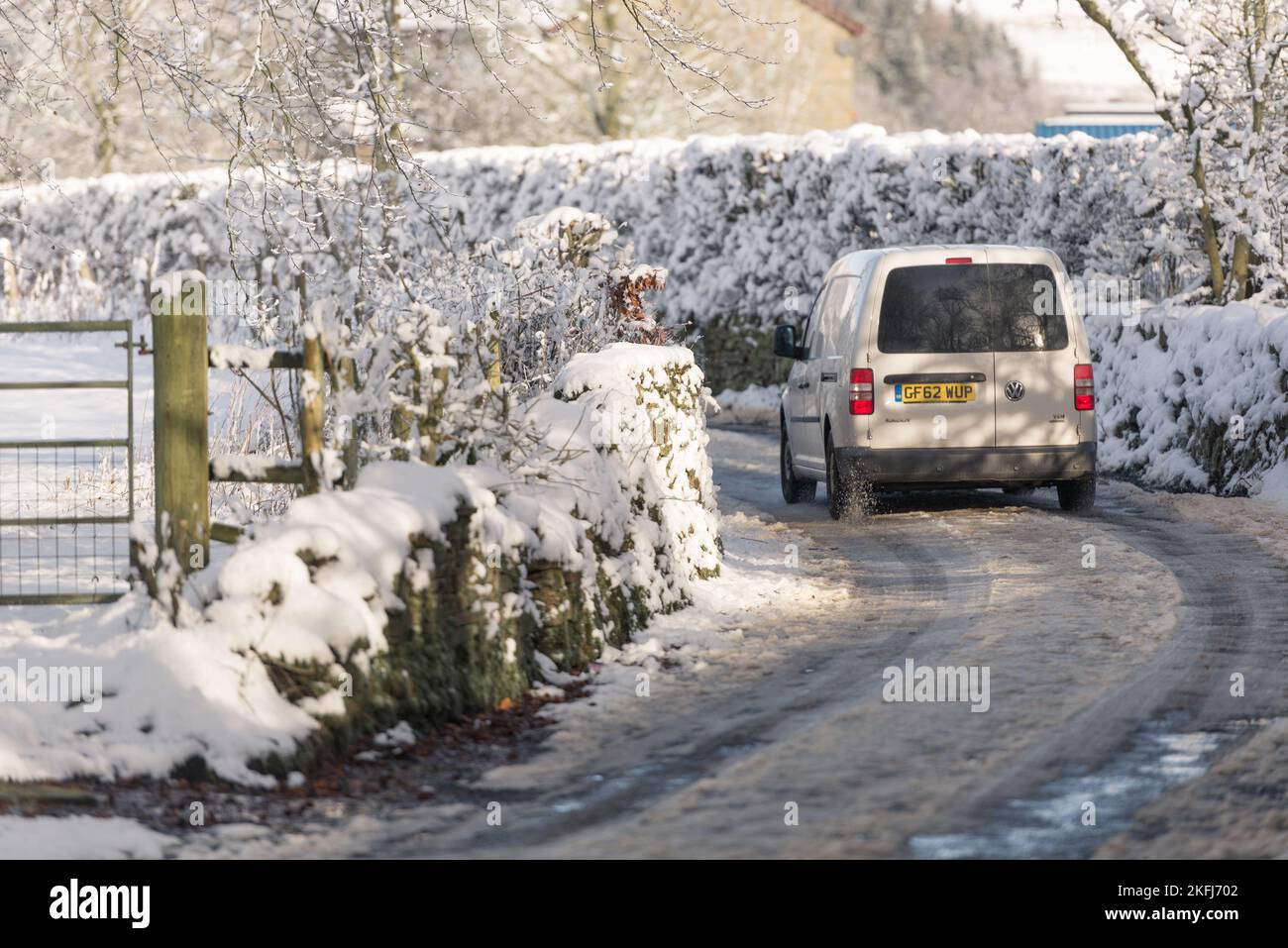 Furgone bianco che viaggia lungo la corsia di campagna nel gelo e nel ghiaccio. Piste da neve sulla corsia Foto Stock
