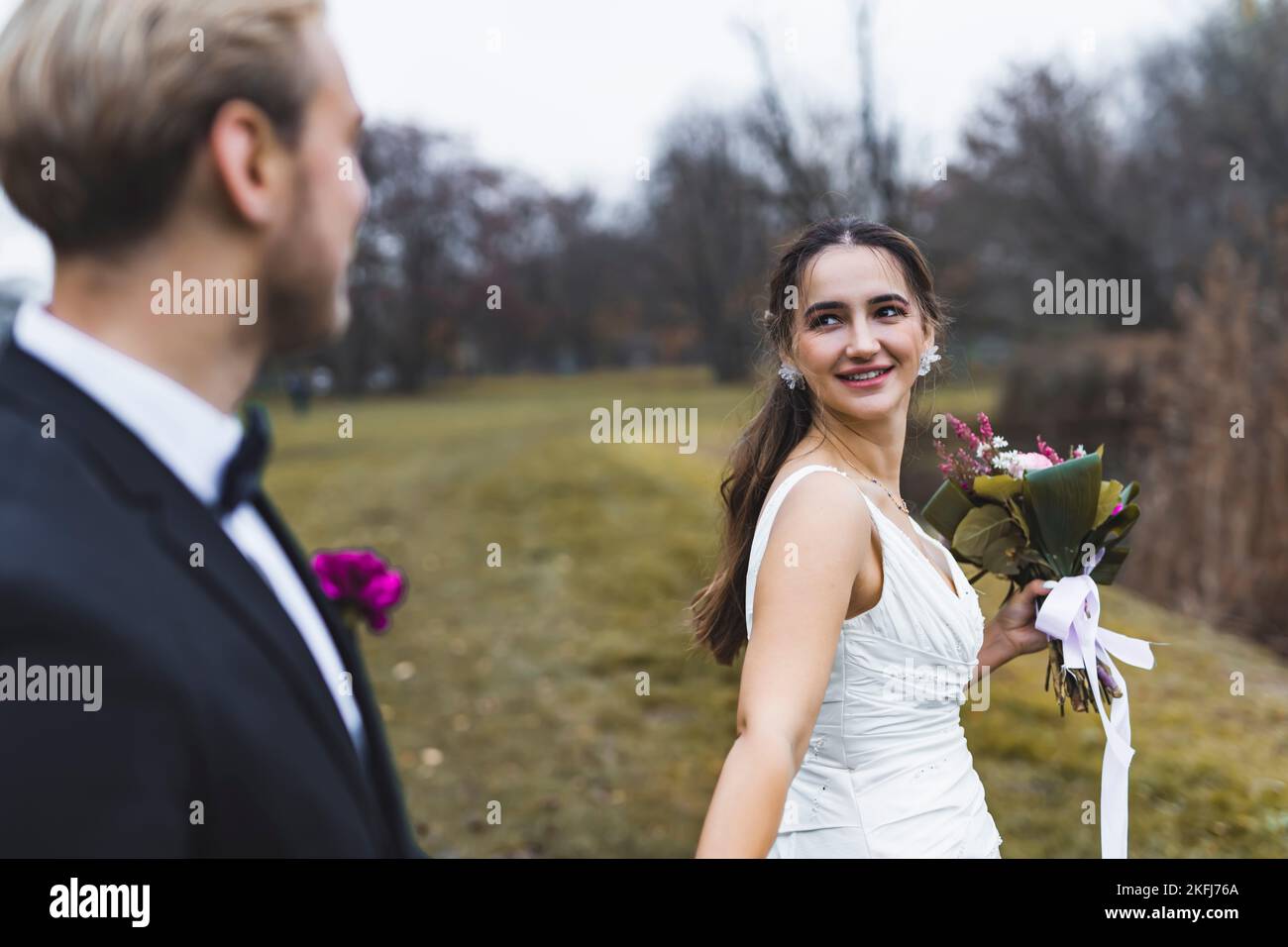 Sposa turca con bel sorriso sul viso che conduce il marito appena sposato. Foto autunnale all'aperto. Concetto di matrimonio e matrimonio. Nuovi inizi. Foto di alta qualità Foto Stock