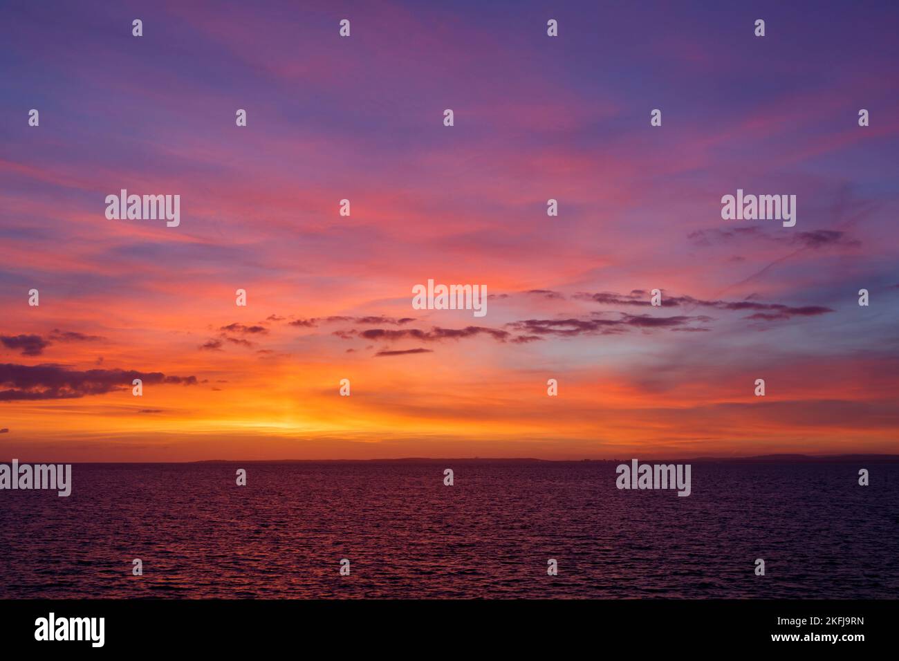 Il sole che tramonta illumina la nuvola con una leggera tonalità di rosa Foto Stock