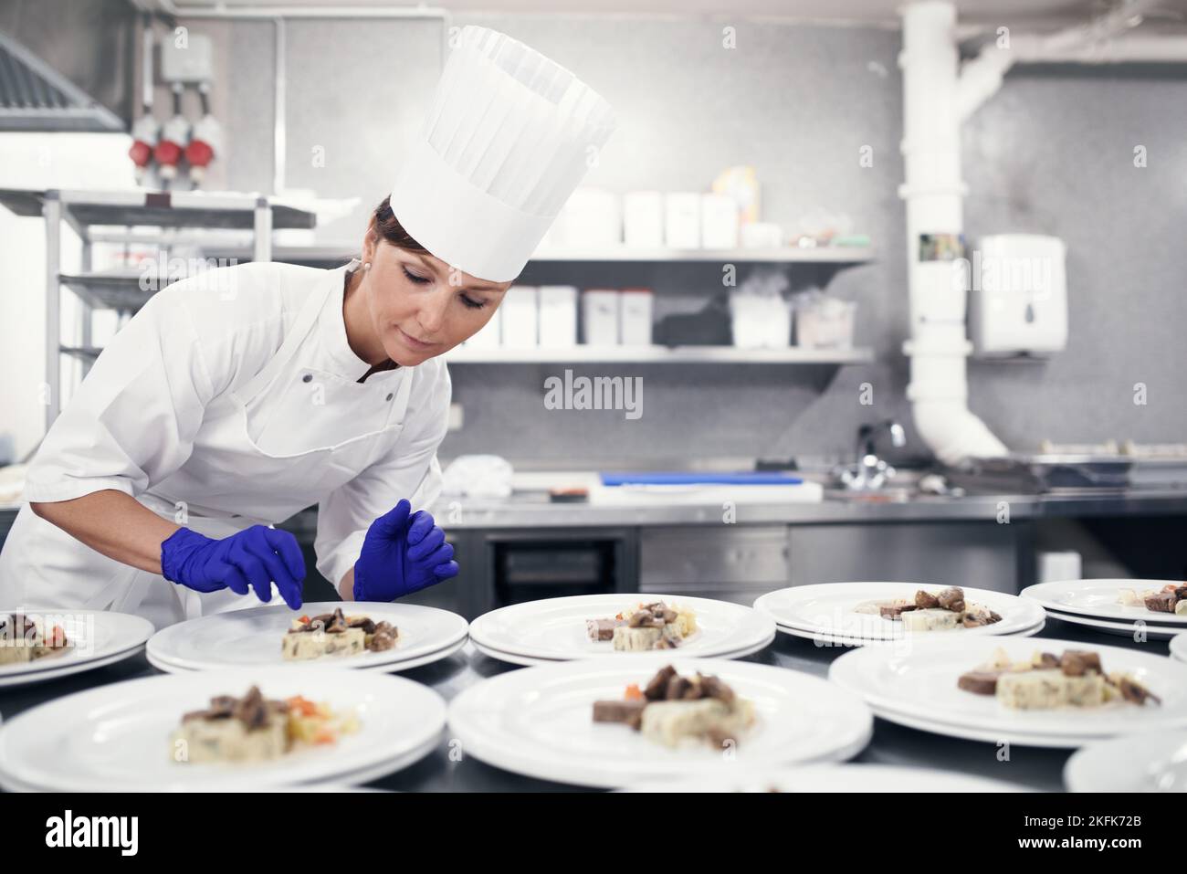 Dalle mani al tavolo. Uno chef che prepara cibo per un servizio di pasto in una cucina professionale. Foto Stock