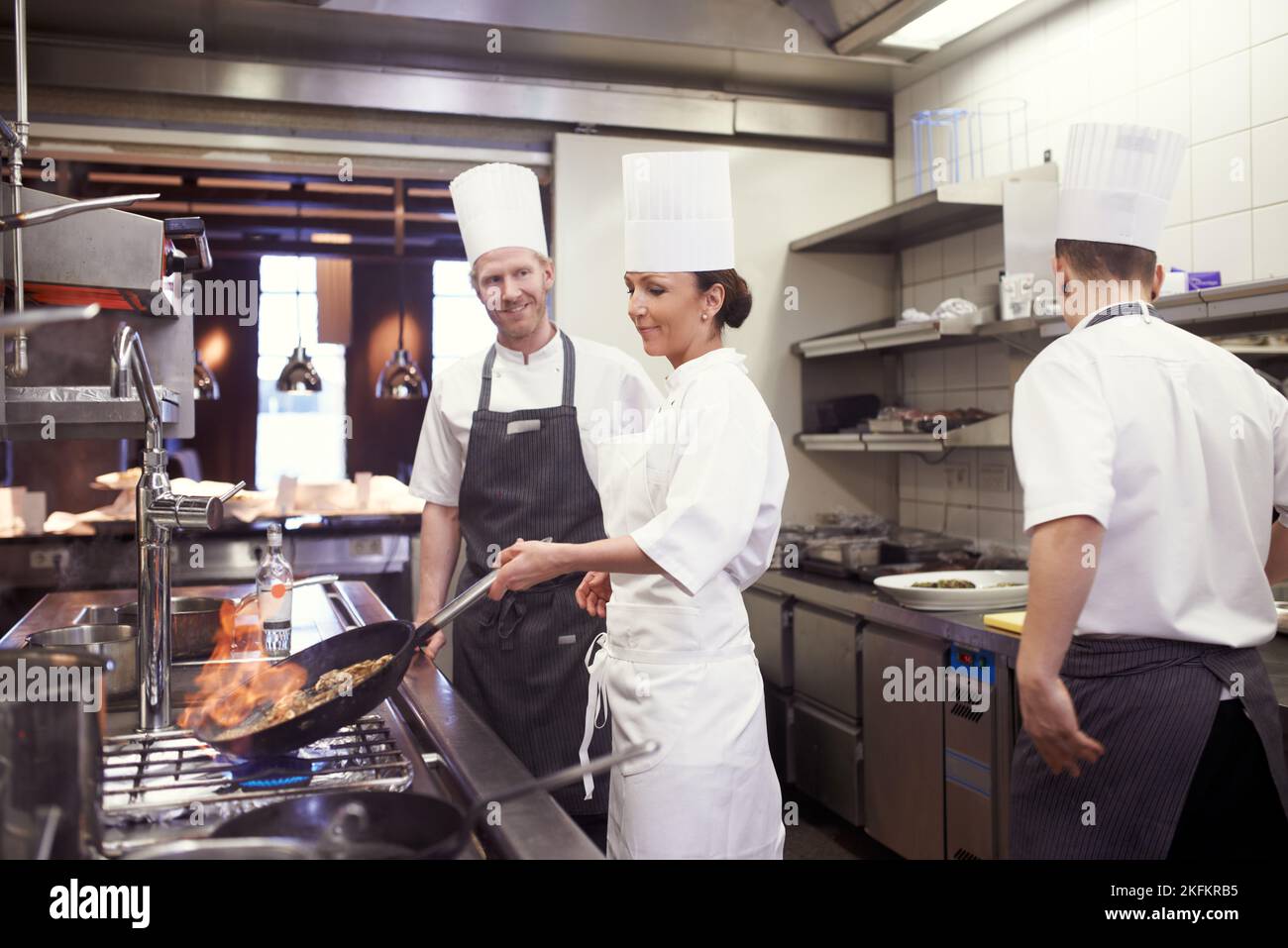 Mostrare ai suoi compagni chef come è fatto. Chef fiammare in una cucina ristorante. Foto Stock