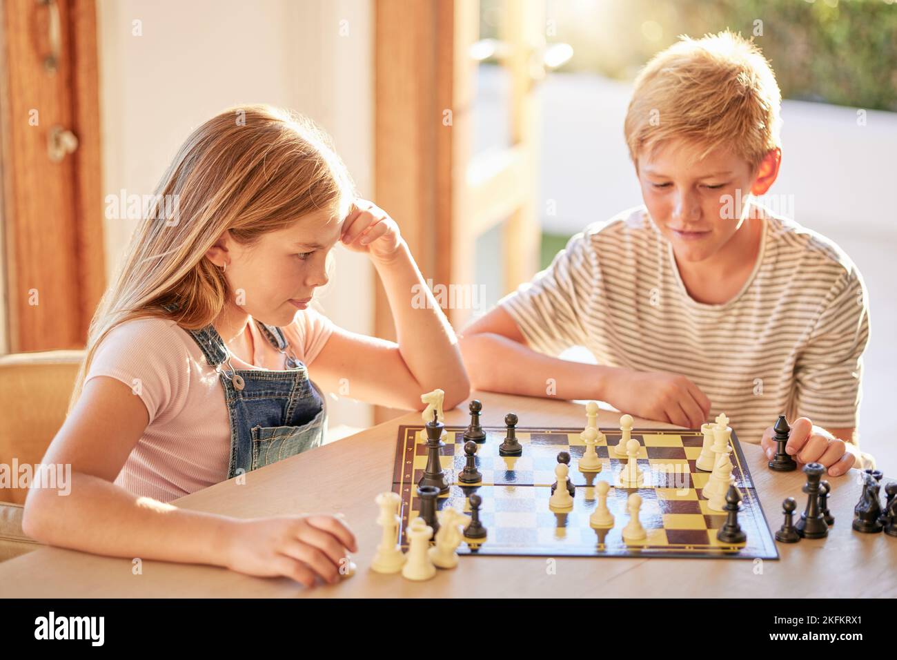 Bambini, scacchi e giochi da tavolo pensando di muoversi con la conoscenza, la strategia e la pianificazione per vincere per lo sviluppo e la crescita a casa. Bambini, fratelli Foto Stock