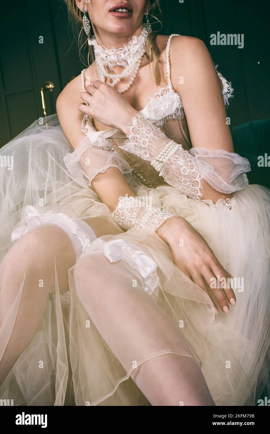 una giovane donna in un vestito del 18th ° secolo e pizzo è seduta nel boudoir regolare la fasciatura sulle sue calze Foto Stock una giovane donna in un vestito del 18th ° secolo e pizzo è seduta nel boudoir regolare la fasciatura sulle sue calze Foto Stock