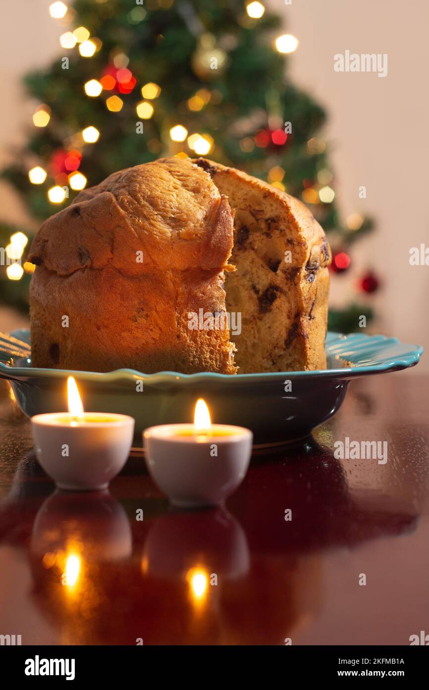 Goiânia, Goias, Brasile – 18 novembre 2022: Un panettone con due candele accese e le luci dell'albero di Natale sfocate sullo sfondo. Foto Stock