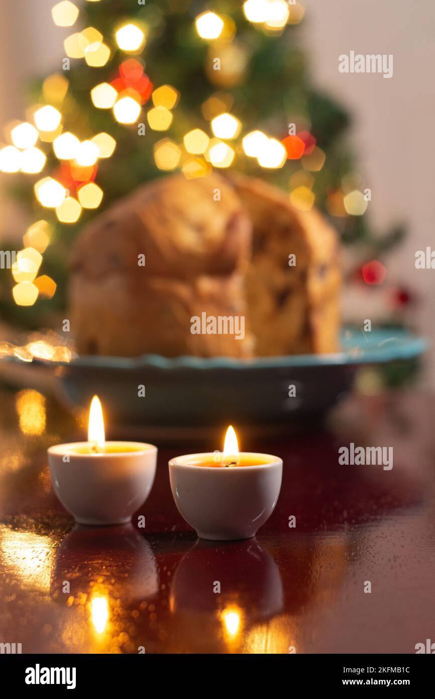 Goiânia, Goias, Brasile – 18 novembre 2022: Un panettone sfocato con due candele accese e le luci dell'albero di Natale sullo sfondo. Foto Stock