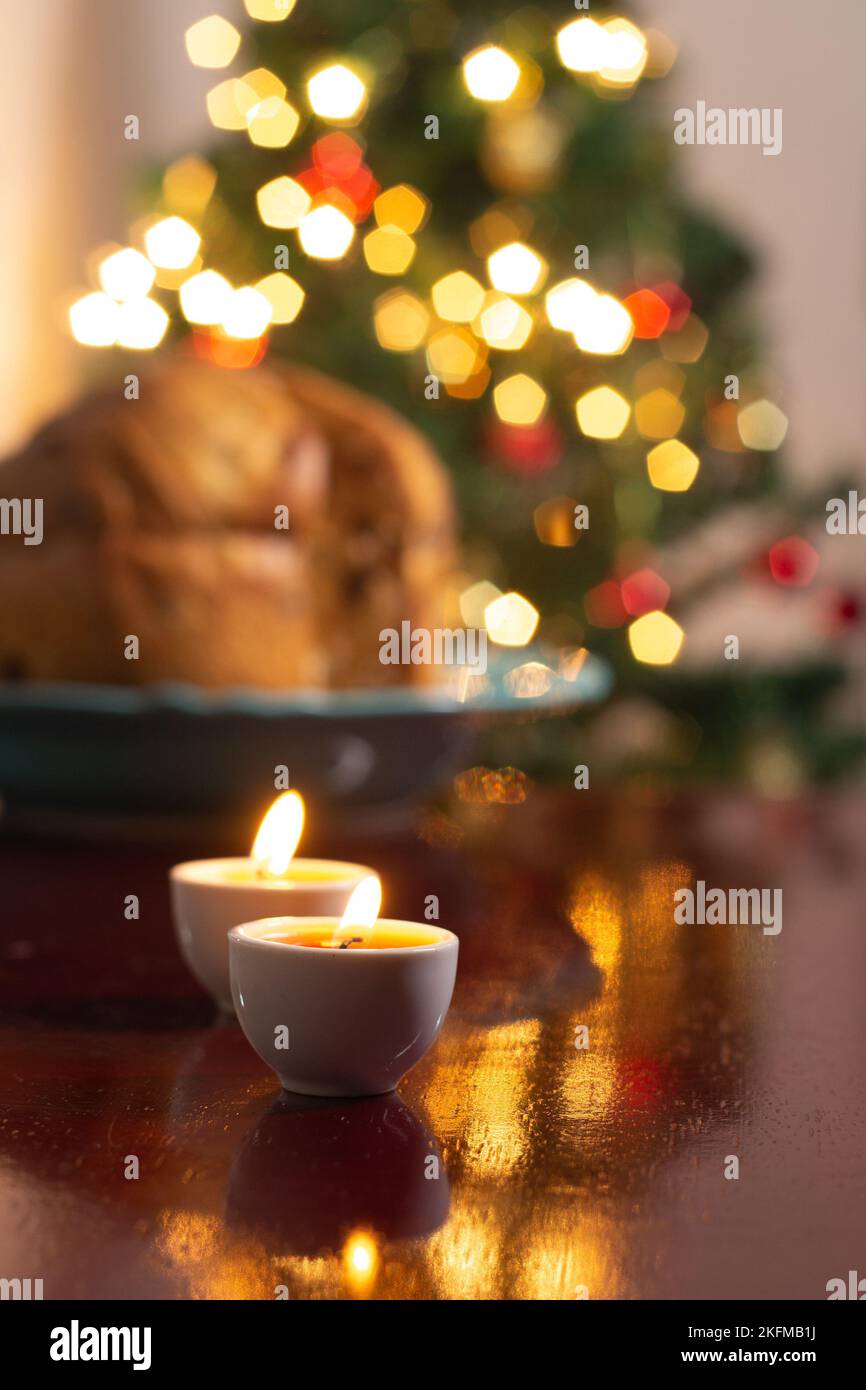 Goiânia, Goias, Brasile – 18 novembre 2022: Un panettone sfocato con due candele accese e le luci dell'albero di Natale sullo sfondo. Foto Stock