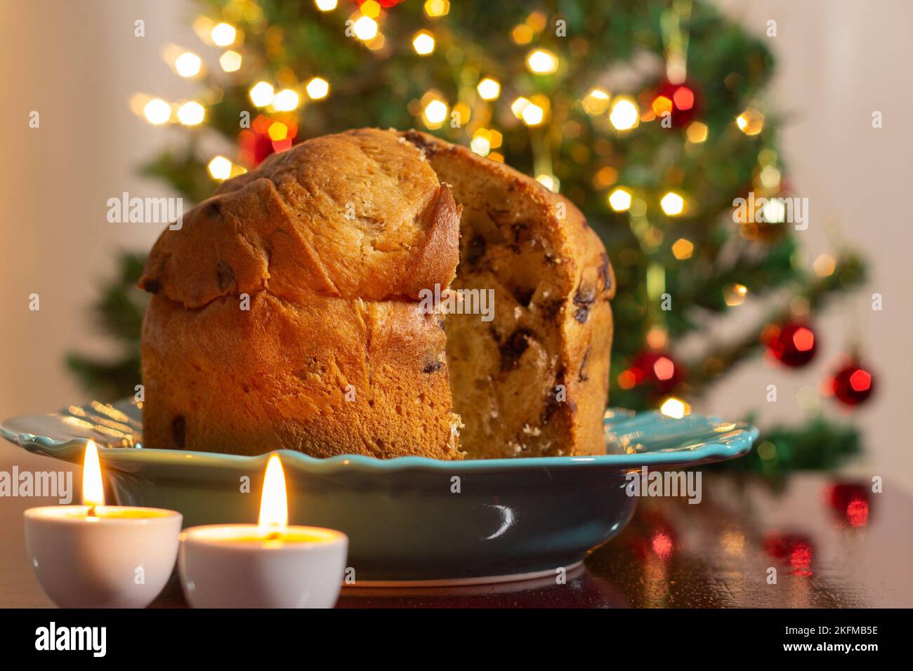 Goiânia, Goias, Brasile – 18 novembre 2022: Un panettone con due candele accese e le luci dell'albero di Natale sfocate sullo sfondo. Foto Stock