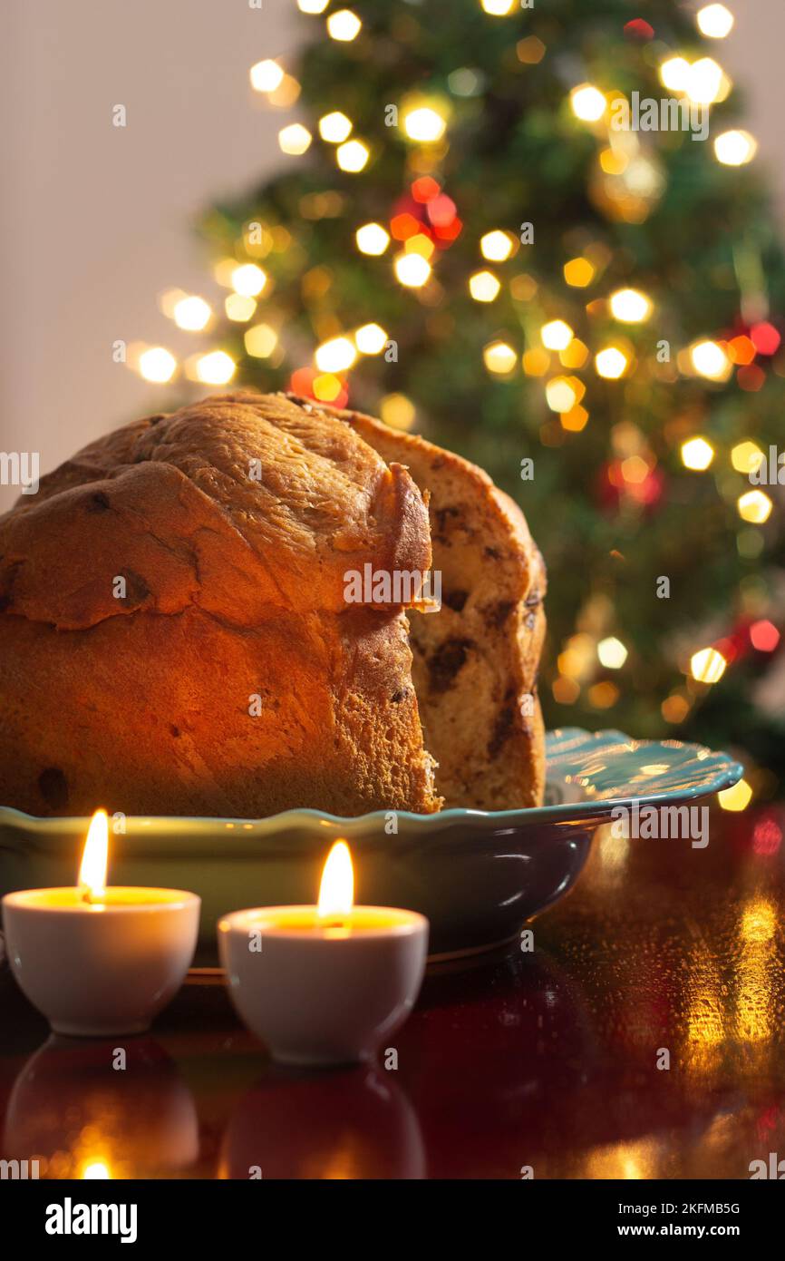 Goiânia, Goias, Brasile – 18 novembre 2022: Un panettone con due candele accese e le luci dell'albero di Natale sfocate sullo sfondo. Foto Stock