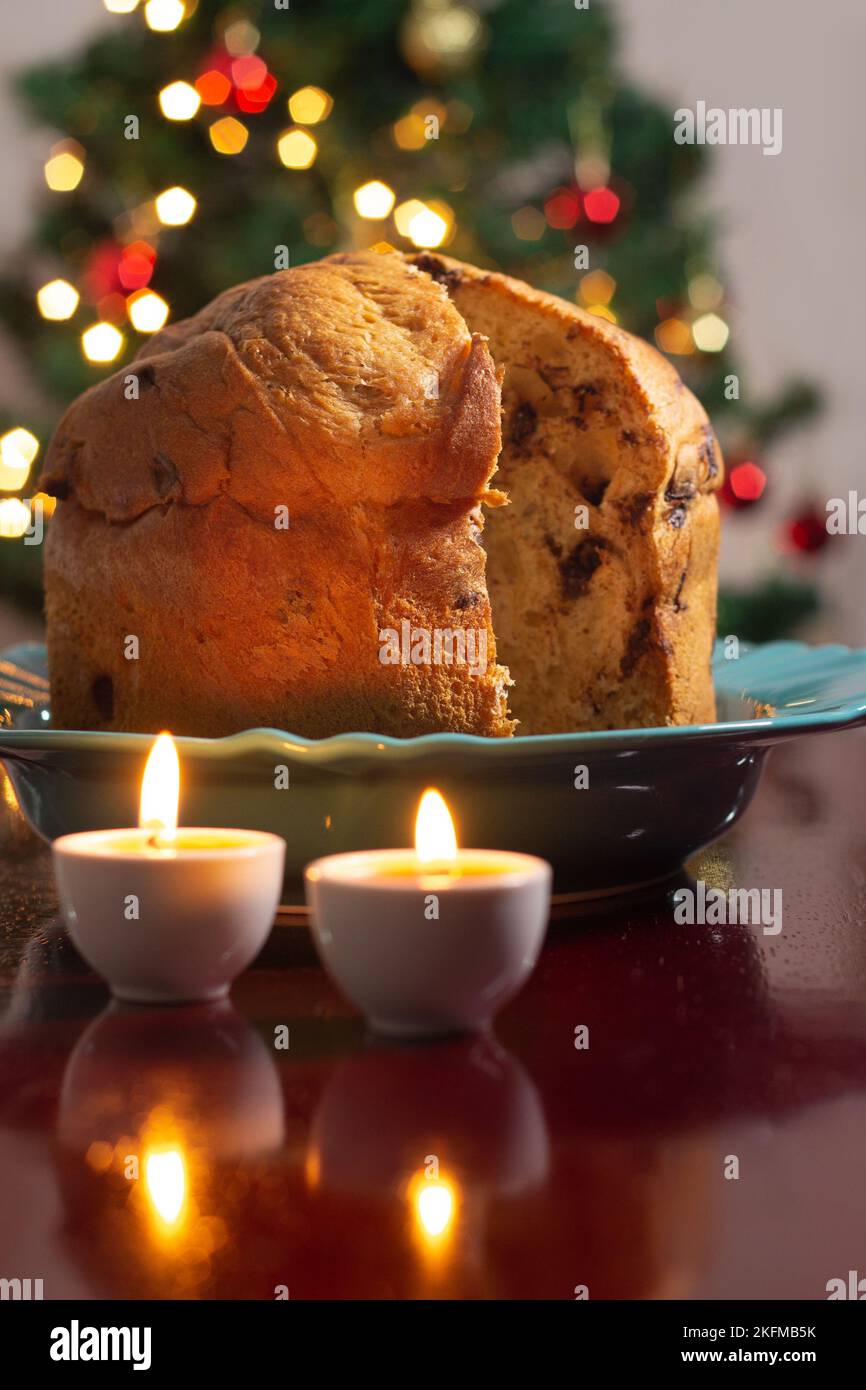 Goiânia, Goias, Brasile – 18 novembre 2022: Un panettone con due candele accese e le luci dell'albero di Natale sfocate sullo sfondo. Foto Stock