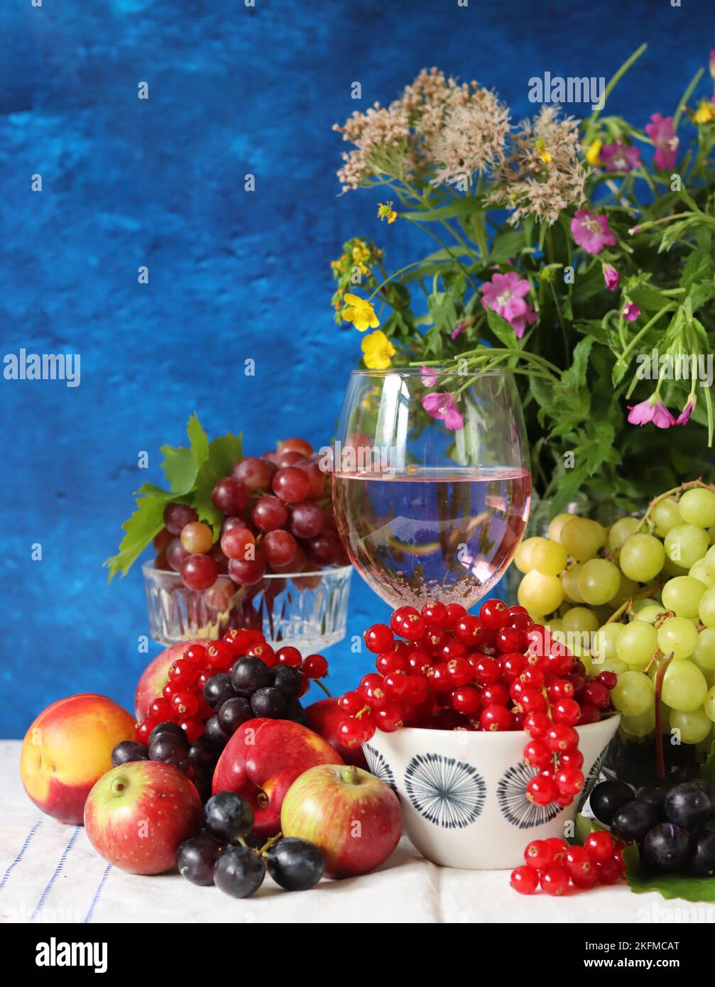 Ancora vita con un bicchiere di vino rosato, frutti di bosco freschi di stagione e frutta. Foto ravvicinata di una bella frutta succosa. Foto Stock
