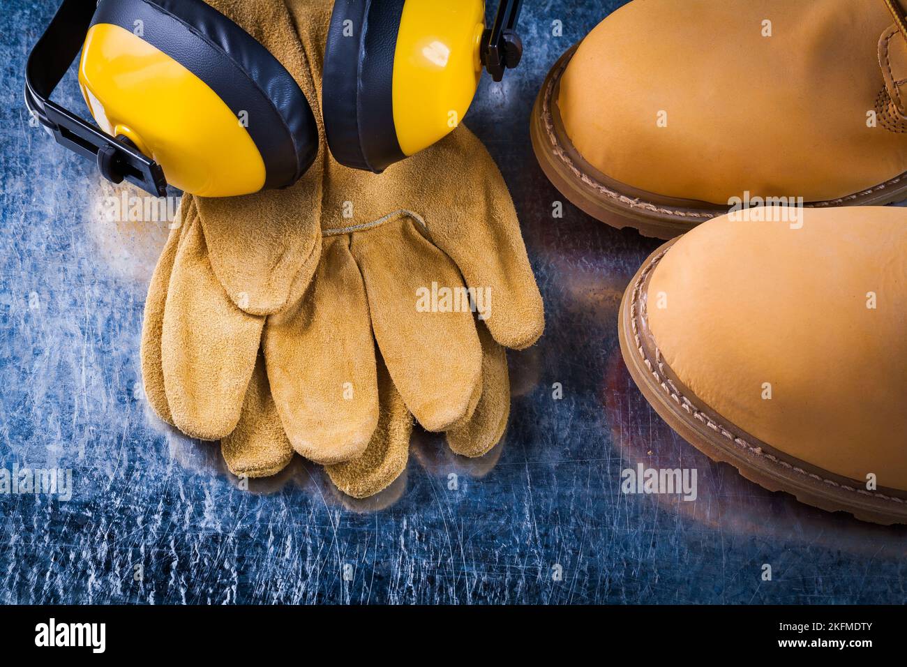 Set di guanti in pelle e cuffie antirumore per calzature antinfortunistiche con design a superficie metallica graffiata. Foto Stock