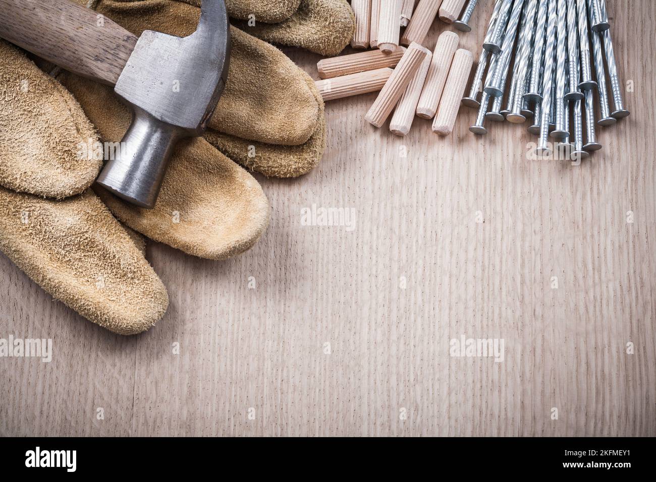 Pila di tasselli in legno martello a artiglio guanti da lavoro in pelle e chiodi in acciaio inossidabile su asse di legno Vista ravvicinata costruzione concetto. Foto Stock