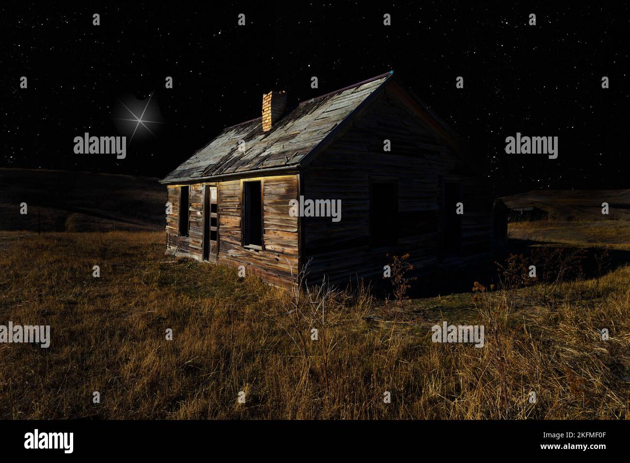 Vecchia casa che ha una luce luminosa nel cielo notturno sopra Foto Stock