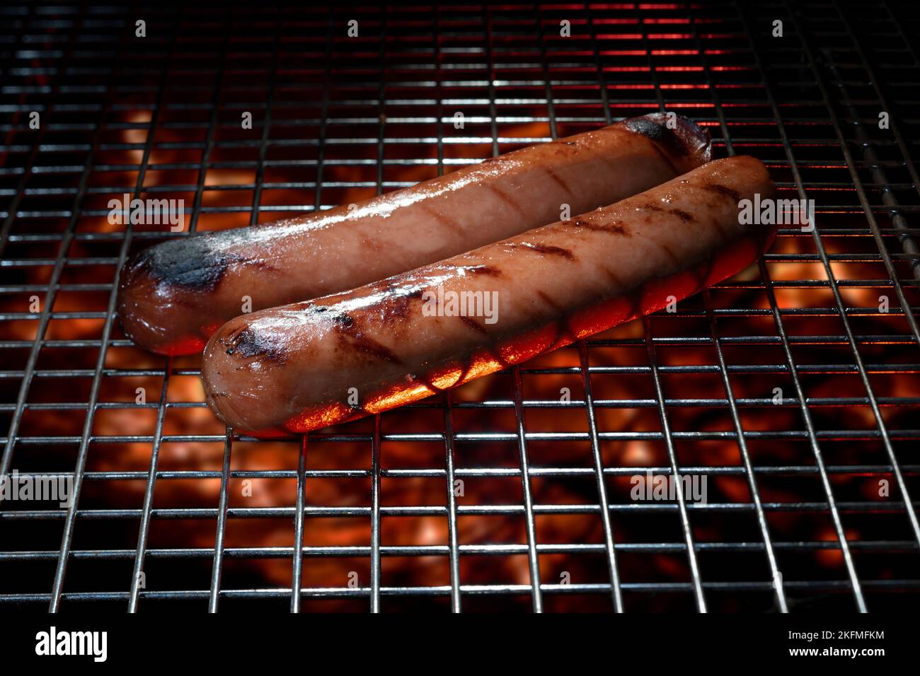 Fuoco sotto un paio di hot dog sulla griglia Foto Stock