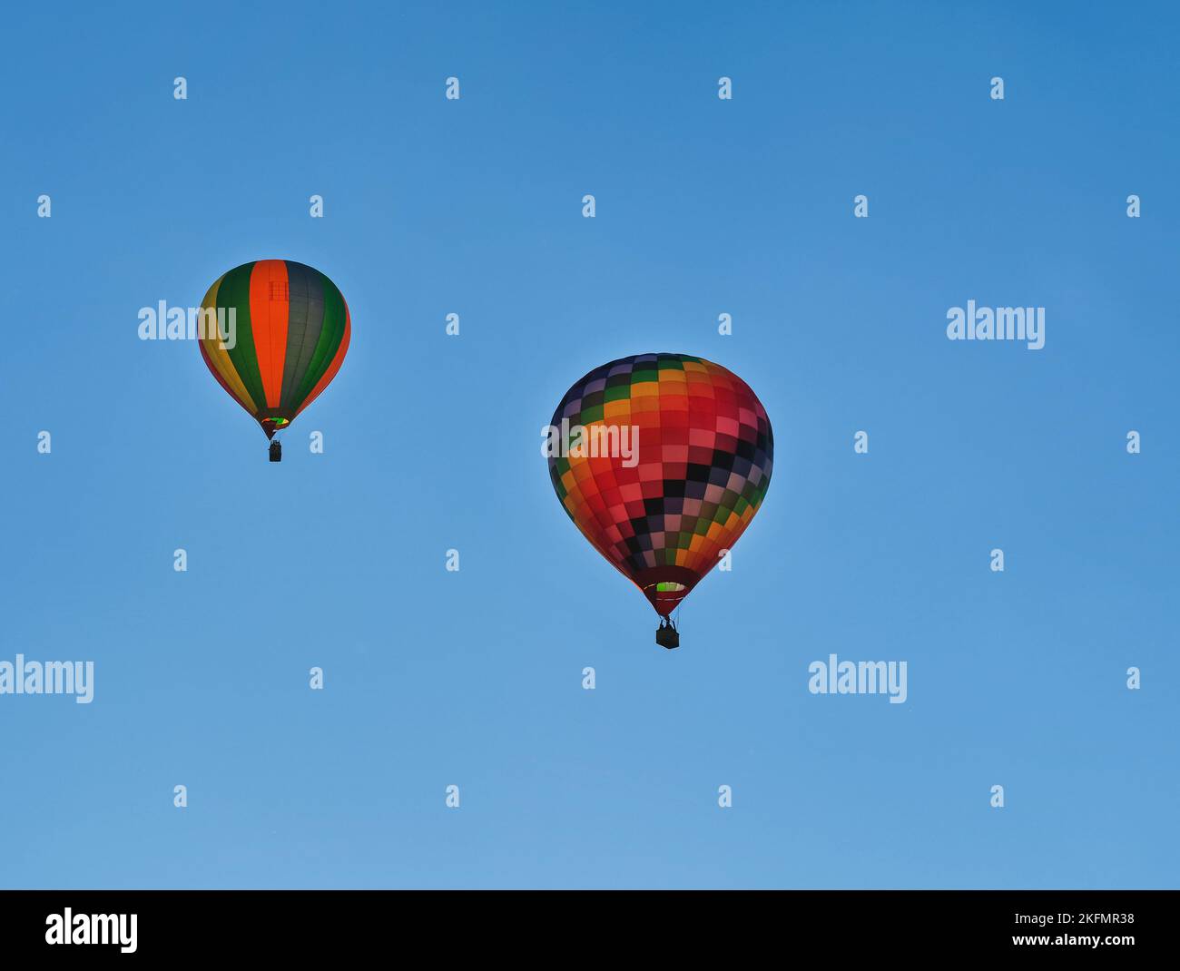 Due coloratissimi mongolfiere che volano attraverso il cielo blu. Foto Stock